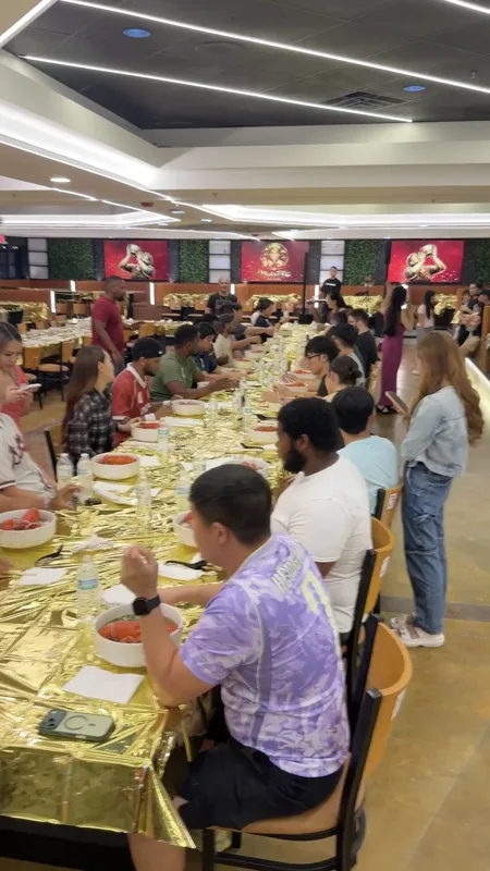 Competitors at the long gold table with a crowd watching behind them